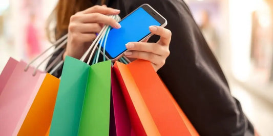 Person with shopping bags using a smartphone.